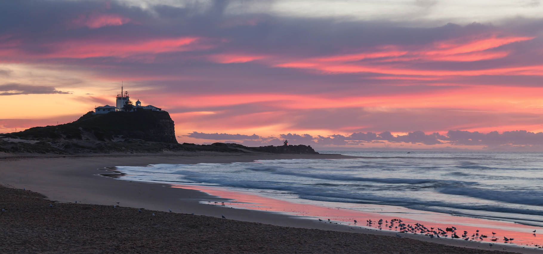 Sunrise at Nobbys Beach and Lighthouse famous landmarks in the harbour city of Newcastle NSW Australia